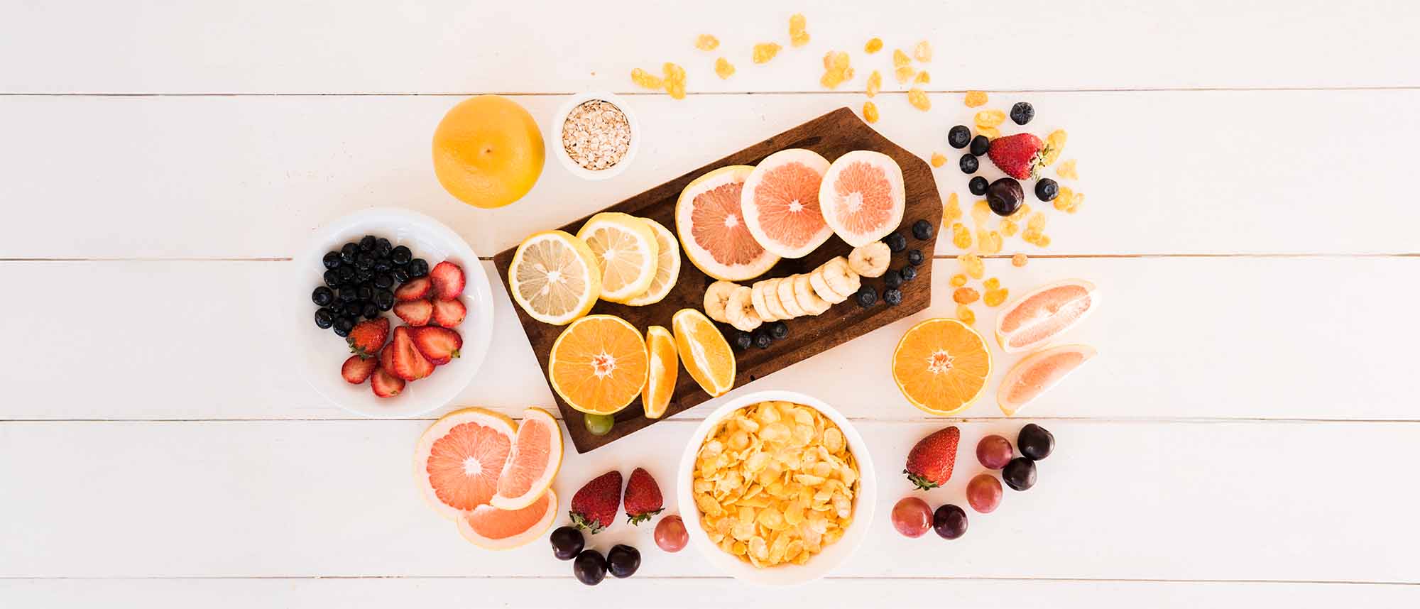 Un grupo de distintos alimentos que son ricos en vitamina C, los cuales son naranjas, fresas, moras, uvas y cereales.