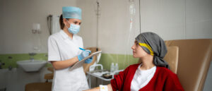 Paciente con leucemia atendida por una enfermera; están en hospital dentro de la habitación de la paciente.