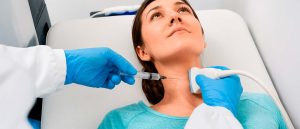 Especialista de la salud aplicando un proceso para una biopsia de tiroides a paciente.