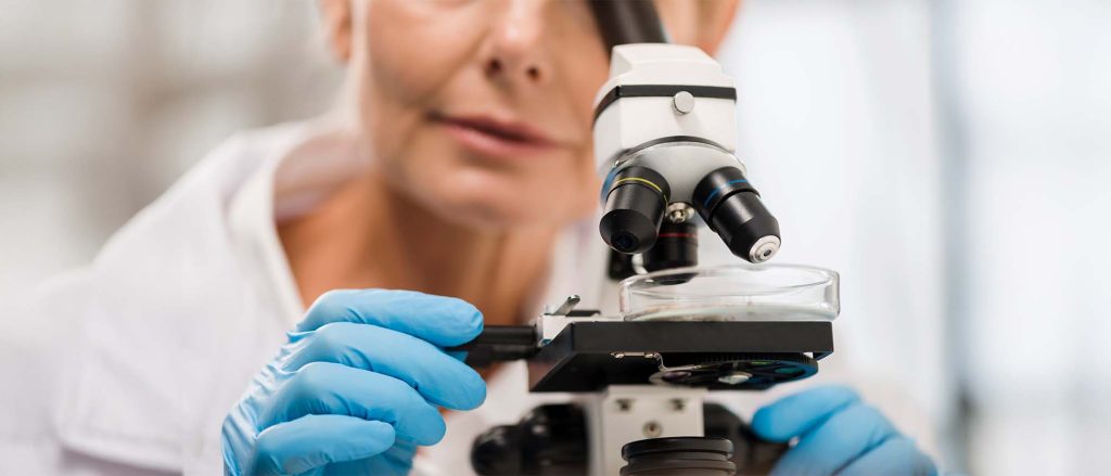 Especialista en biopsia, citología e histopatología, analizando muestra en un microscopio.